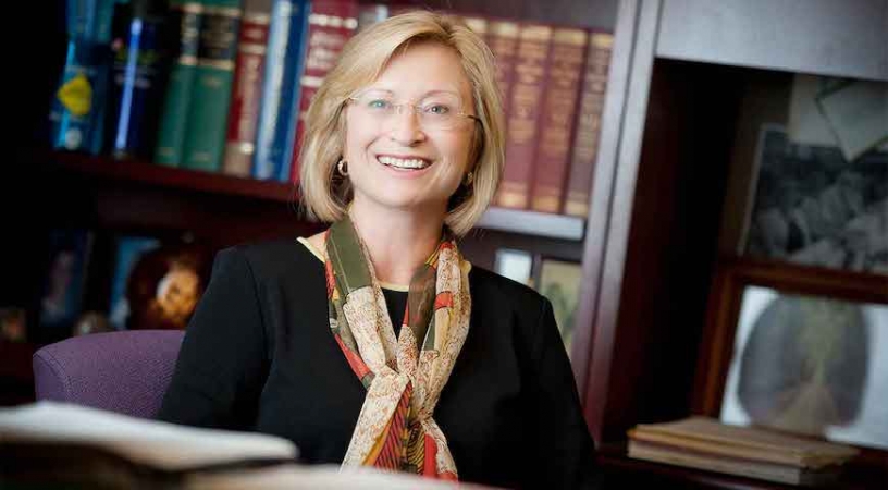 Professor Sandra A. Brown in her office in front of a bookshelf filled with books.